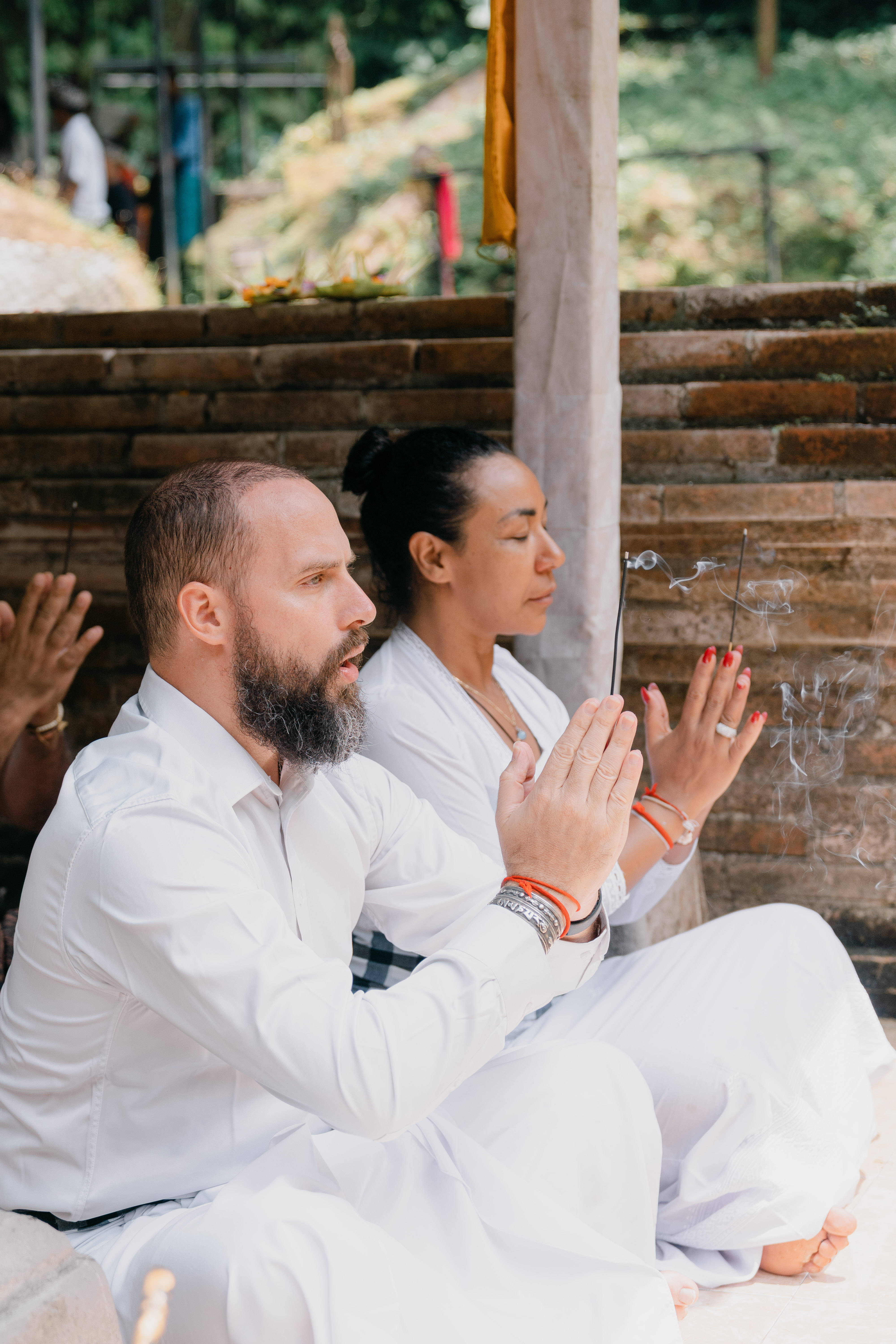 Gizel in white robes, sitting in prayer with incense — sacred ceremony